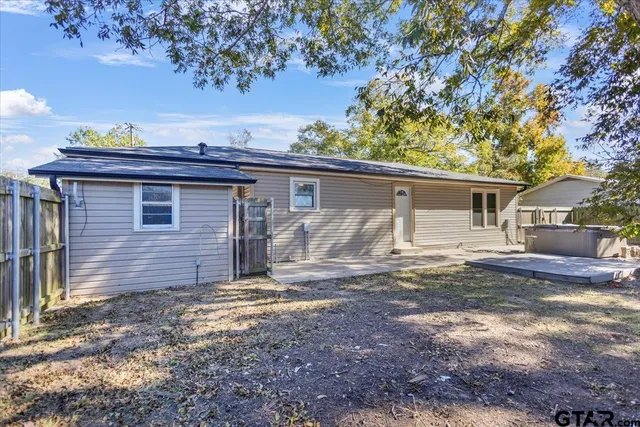 a view of a house with a small yard and large tree