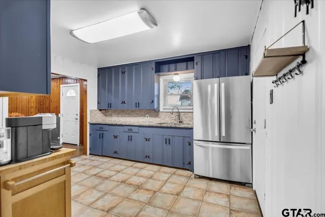 a kitchen with granite countertop a refrigerator and a stove top oven