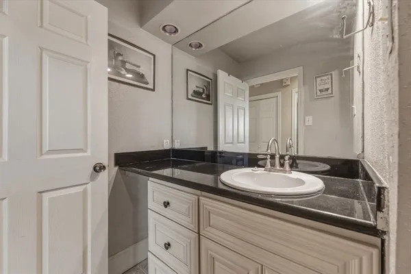 a bathroom with a granite countertop sink and a mirror