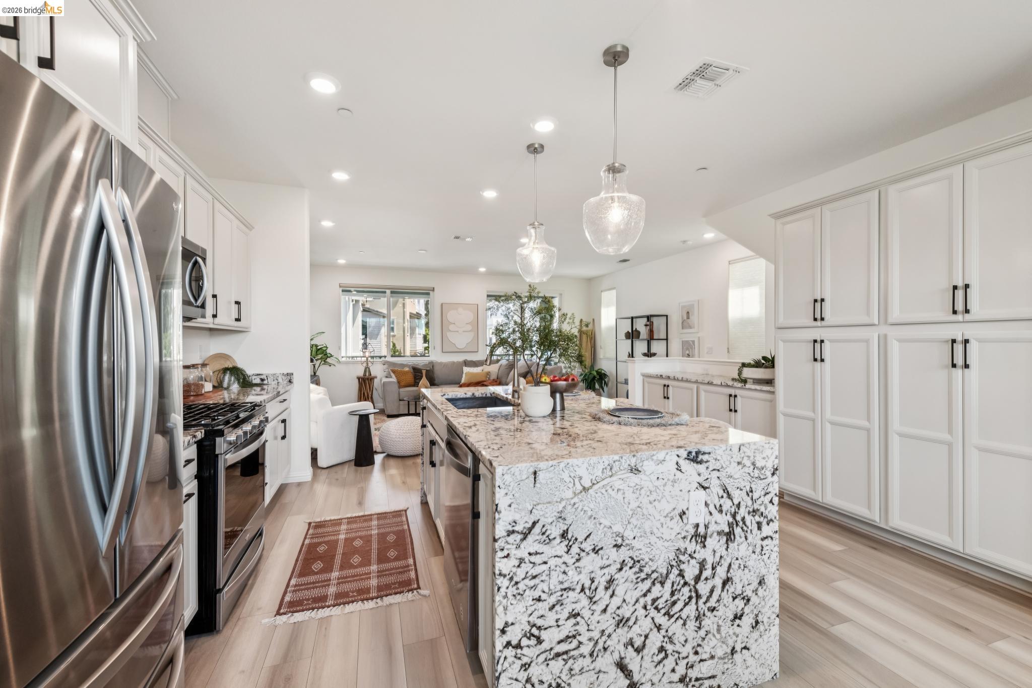 24157 Amaranth Loop Hayward, CA 94541 - Photo 24 of 63 Gourmet kitchen featuring a substantial island with stone countertop, stainless steel appliances, abundant white cabinetry, recessed lighting, and wood-finish flooring