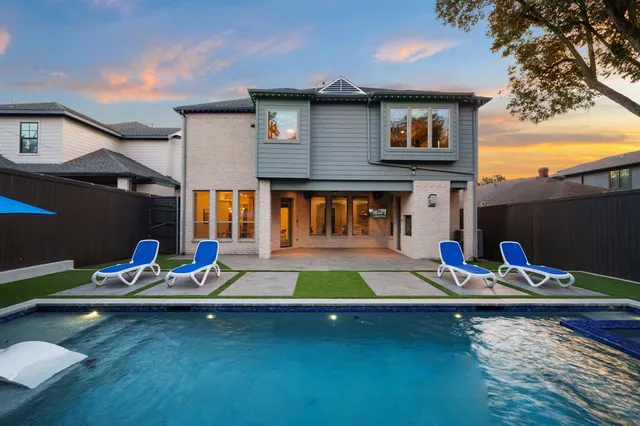 a view of swimming pool with lawn chairs and plants