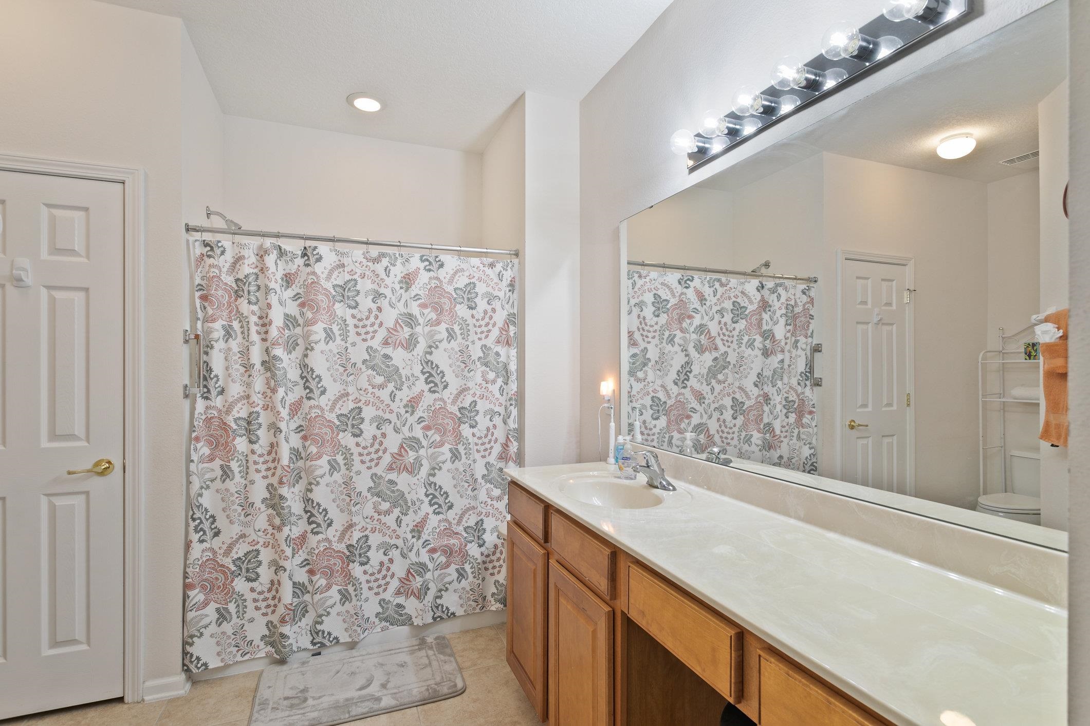 554 Wooded Crossing Circle St. Augustine, FL 32084 - Photo 22 of 43 a bathroom with a granite countertop sink a shower and a mirror