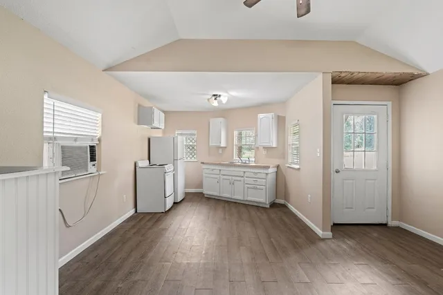a kitchen with white cabinets and wooden floor
