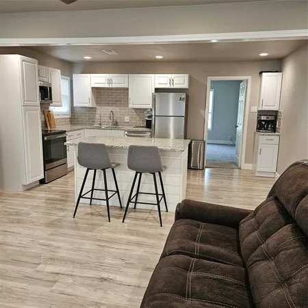 a living room with stainless steel appliances kitchen island granite countertop furniture and a wooden floor
