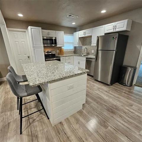 a kitchen with stainless steel appliances granite countertop a refrigerator and a stove