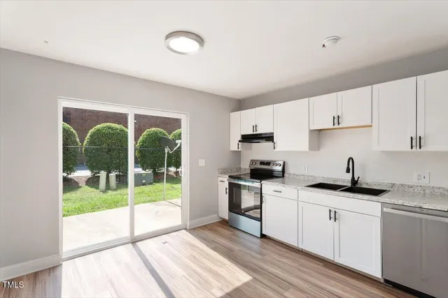 a kitchen with granite countertop a stove a sink and a refrigerator