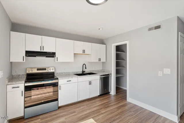 a kitchen with stainless steel appliances a stove and white cabinets