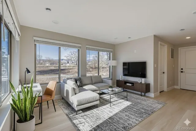 a living room with furniture a flat screen tv and a floor to ceiling window