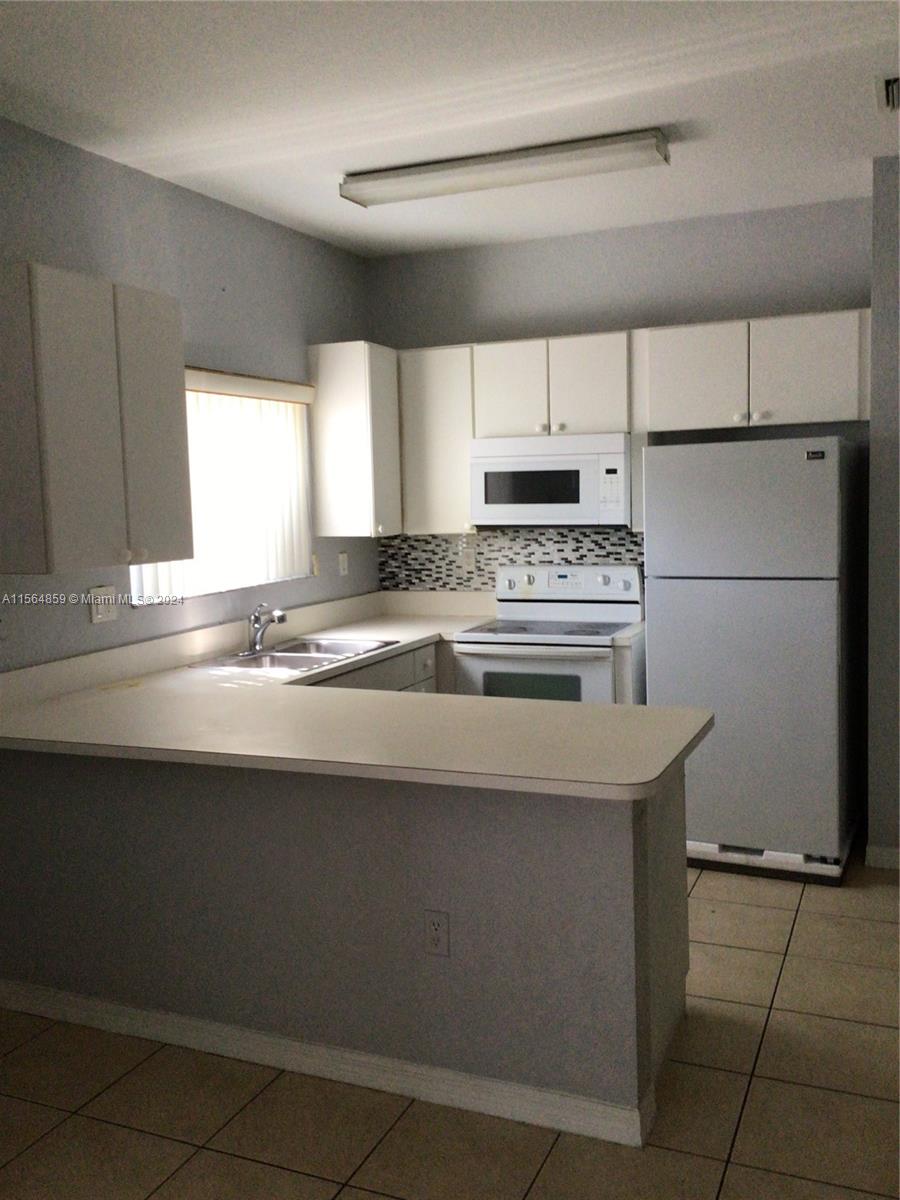 4941 Southwest 135th Way Miramar, FL 33027 - Photo 7 of 11 a kitchen with granite countertop a sink cabinets and stainless steel appliances