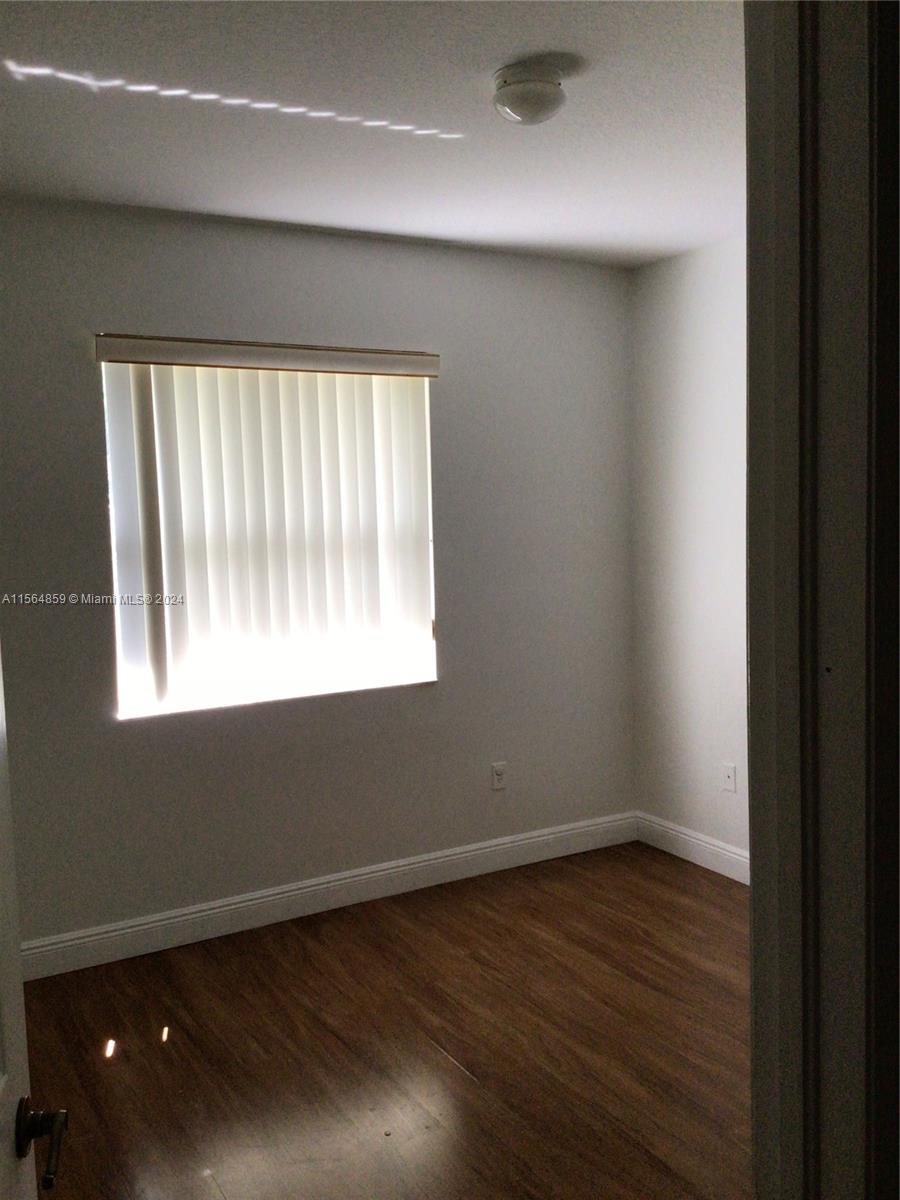 4941 Southwest 135th Way Miramar, FL 33027 - Photo 8 of 11 en empty room with wooden floor and windows