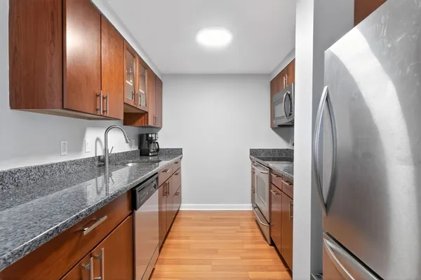 a kitchen with stainless steel appliances granite countertop a refrigerator a stove and a sink