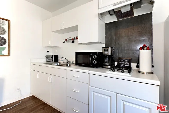 a kitchen with a sink and a stove with wooden floor