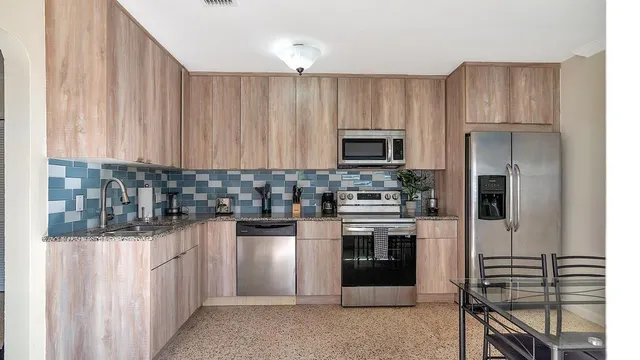 a kitchen with kitchen island granite countertop wooden cabinets and stainless steel appliances