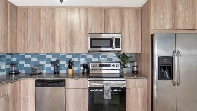 a kitchen with stainless steel appliances granite countertop a refrigerator sink and stove