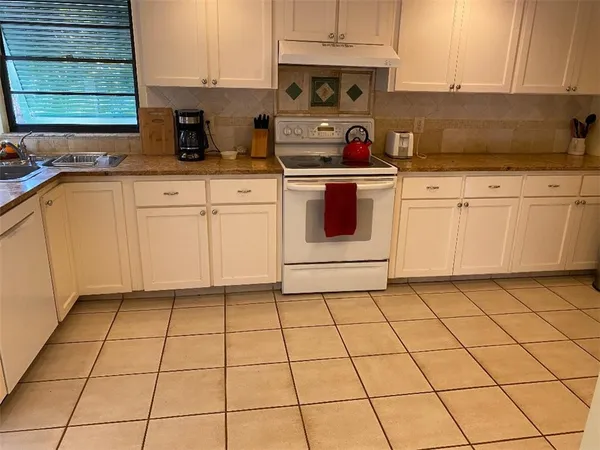 a kitchen with granite countertop white cabinets and white appliances