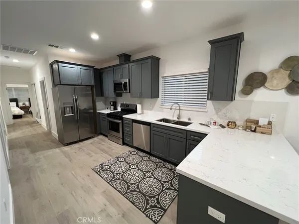 a kitchen with stainless steel appliances kitchen island granite countertop a sink refrigerator and cabinets