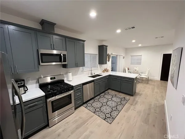 a large white kitchen with stainless steel appliances kitchen island granite countertop a stove a sink a refrigerator a microwave and cabinets