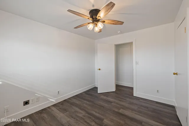 an empty room with wooden floor and ceiling fan