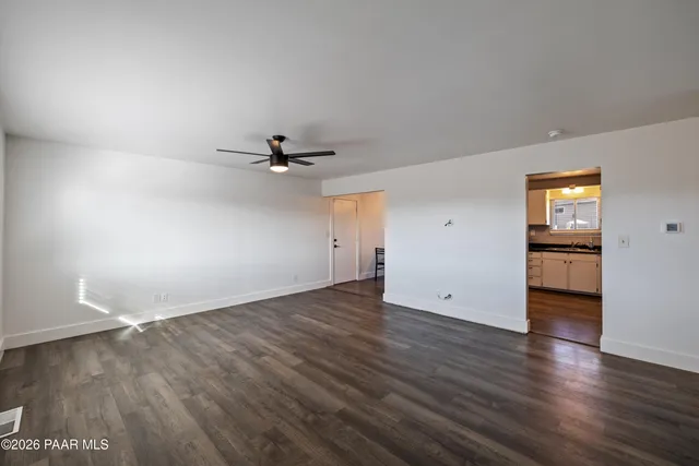 an empty room with wooden floor cabinet and windows