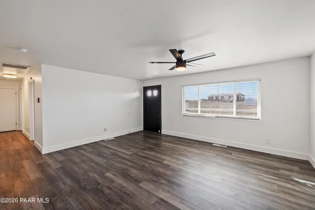 a view of empty room with wooden floor and ceiling fan