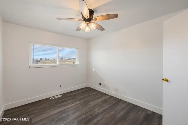 an empty room with wooden floor and ceiling fan