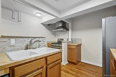 a kitchen with a sink cabinets stainless steel appliances and wooden floor
