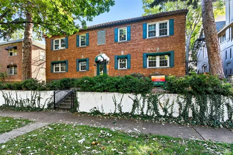 a front view of a house with a garden and tree