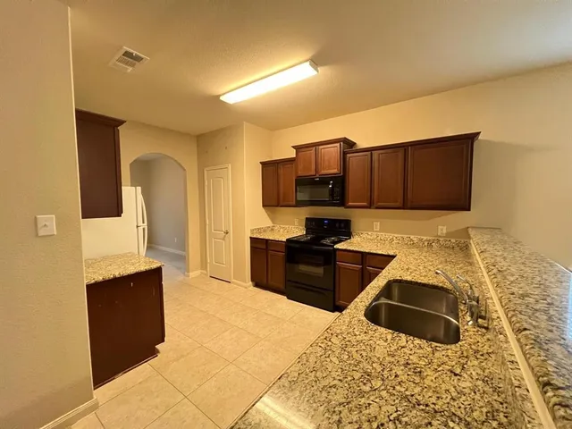 a kitchen with stainless steel appliances granite countertop a stove a sink and a microwave