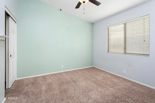 an empty room with a window and a ceiling fan