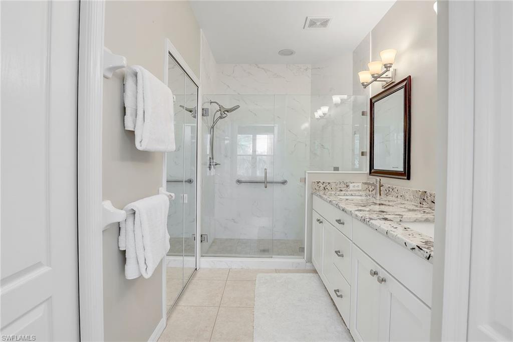 9189 Spring Run Boulevard, Unit 1908 Estero, FL 34135 - Photo 14 of 33 a bathroom with a granite countertop sink mirror and a shower