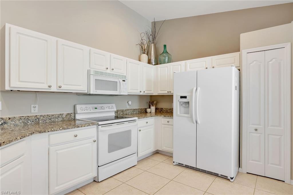 9189 Spring Run Boulevard, Unit 1908 Estero, FL 34135 - Photo 4 of 33 a kitchen with white cabinets and white appliances