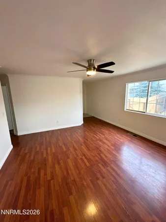 an empty room with wooden floor fan and windows