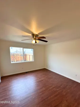 an empty room with wooden floor chandelier fan and windows