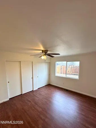 an empty room with wooden floor ceiling fan and windows
