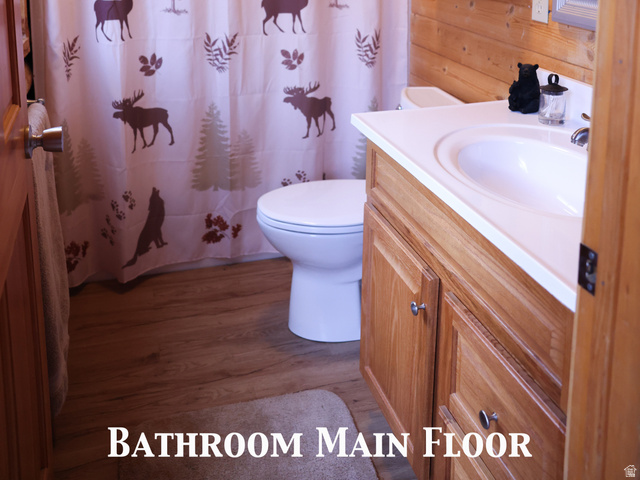 15253 Mill Road, Unit 62 Huntsville, UT 84317 - Photo 6 of 48 Bathroom featuring plank wood walls and ceiling, a single vanity with a white countertop and wood-finish cabinetry, a white toilet, and wood-finish flooring