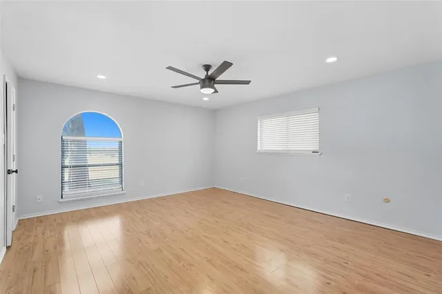 an empty room with windows and ceiling fan