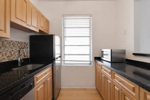a kitchen with granite countertop a refrigerator and a sink
