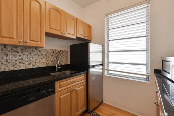 a kitchen with stainless steel appliances granite countertop white cabinets and a window