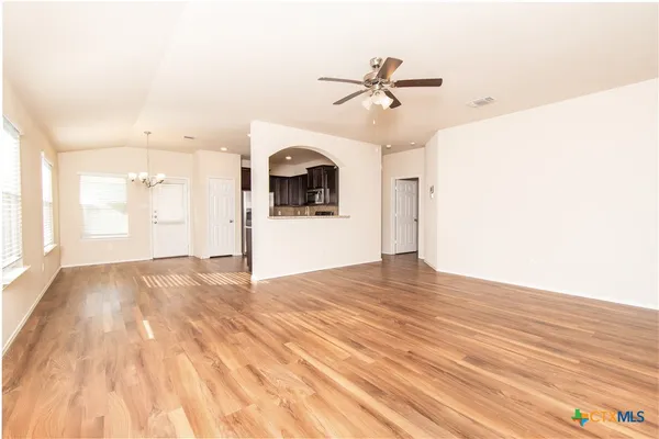 a view of empty room with wooden floor and ceiling fan