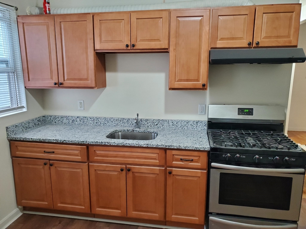 5 Coleman Street, Unit 2 Boston, MA 02125 - Photo 2 of 9 a kitchen with granite countertop stainless steel appliances white cabinets granite counter tops and a wooden floor