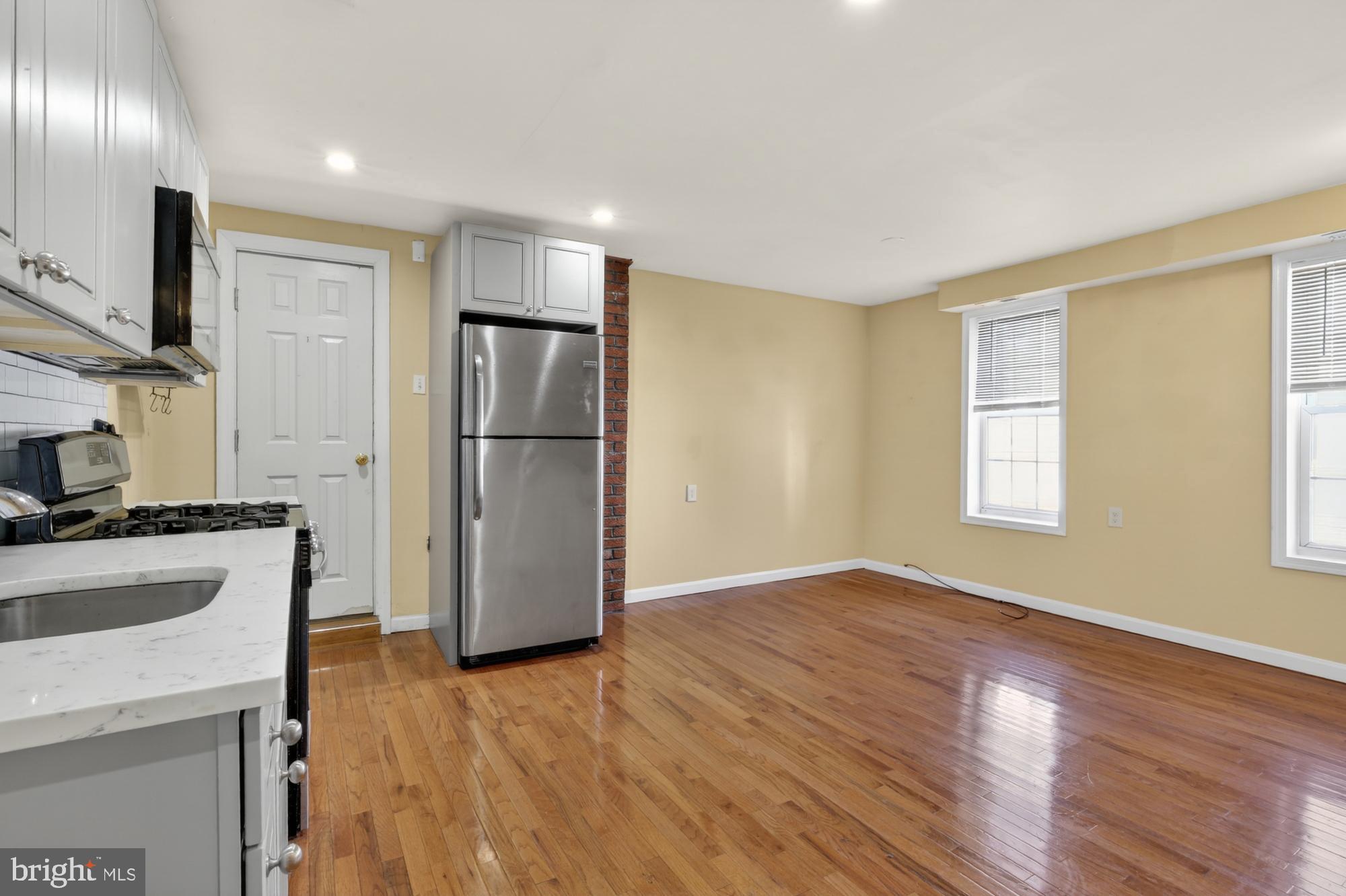 1400 South Chadwick Street, Unit 2 Philadelphia, PA 19146 - Photo 4 of 20 a kitchen with stainless steel appliances granite countertop a refrigerator a stove and a sink with wooden floor