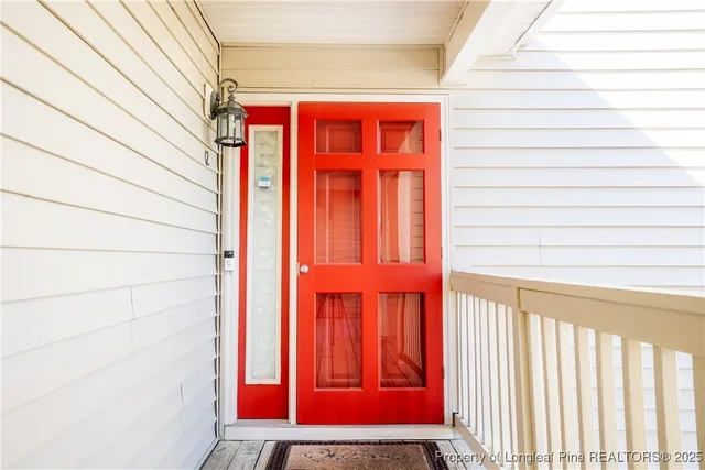 a balcony with red door and wooden floor