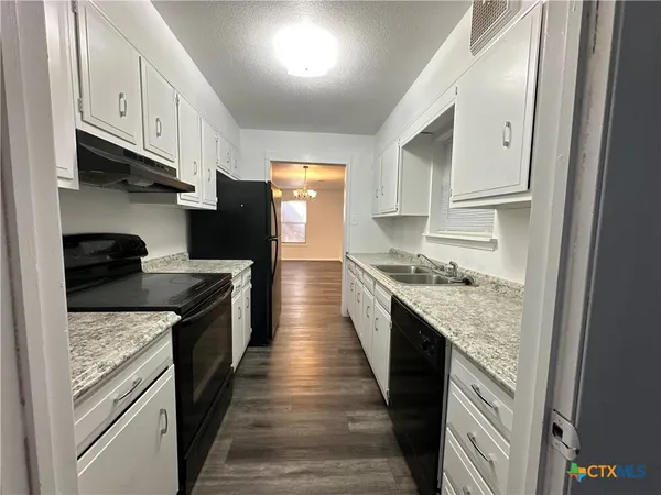 a kitchen with granite countertop a sink stove and refrigerator