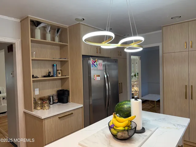a kitchen with a refrigerator and a view of living room