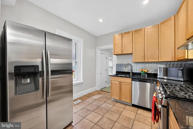 a kitchen with stainless steel appliances granite countertop a refrigerator a stove and a sink with wooden floor