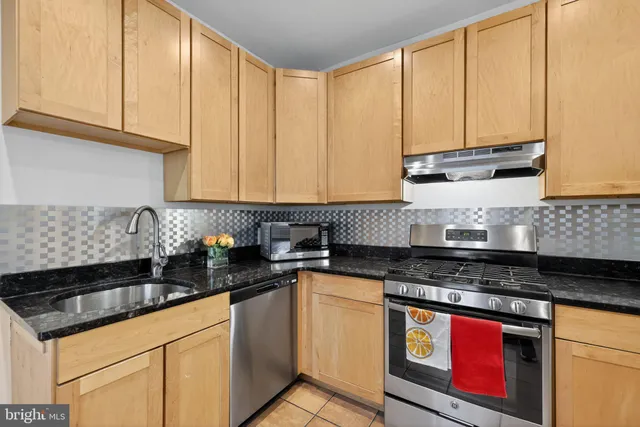 a kitchen with granite countertop a sink a stove and cabinets
