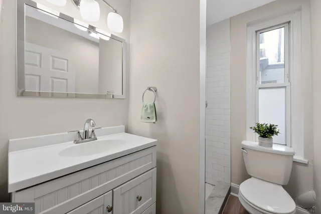 a bathroom with a sink a mirror a toilet and a window