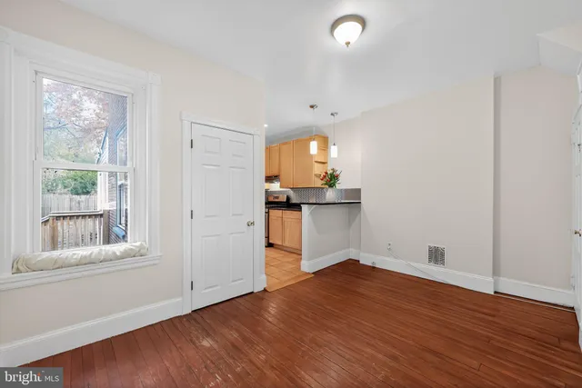 a view of empty room with wooden floor and fan