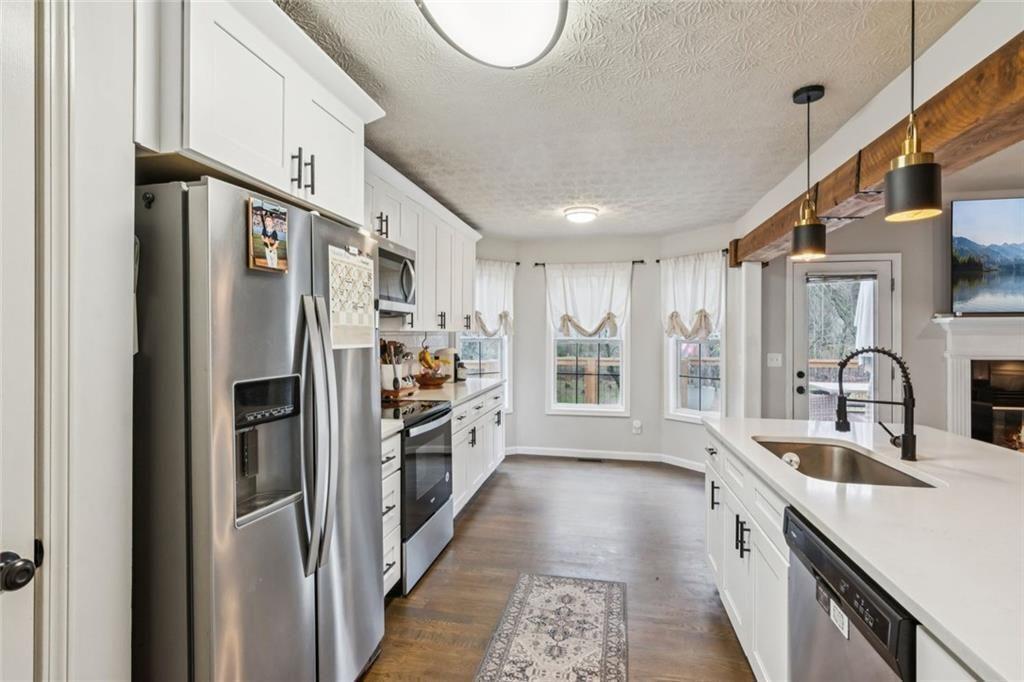 5595 Vaughn Road Woodstock, GA 30188 - Photo 15 of 42 a kitchen with stainless steel appliances granite countertop a refrigerator a sink dishwasher a stove and a dining table with wooden floor