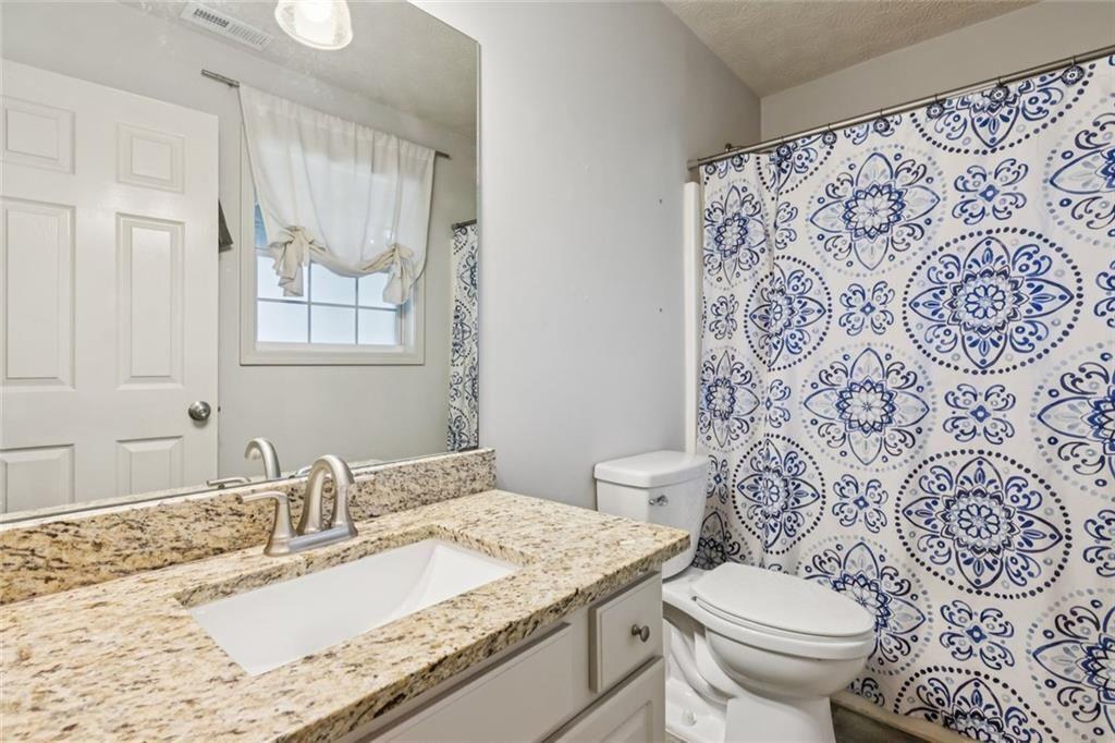 5595 Vaughn Road Woodstock, GA 30188 - Photo 30 of 42 a bathroom with a granite countertop toilet sink and mirror